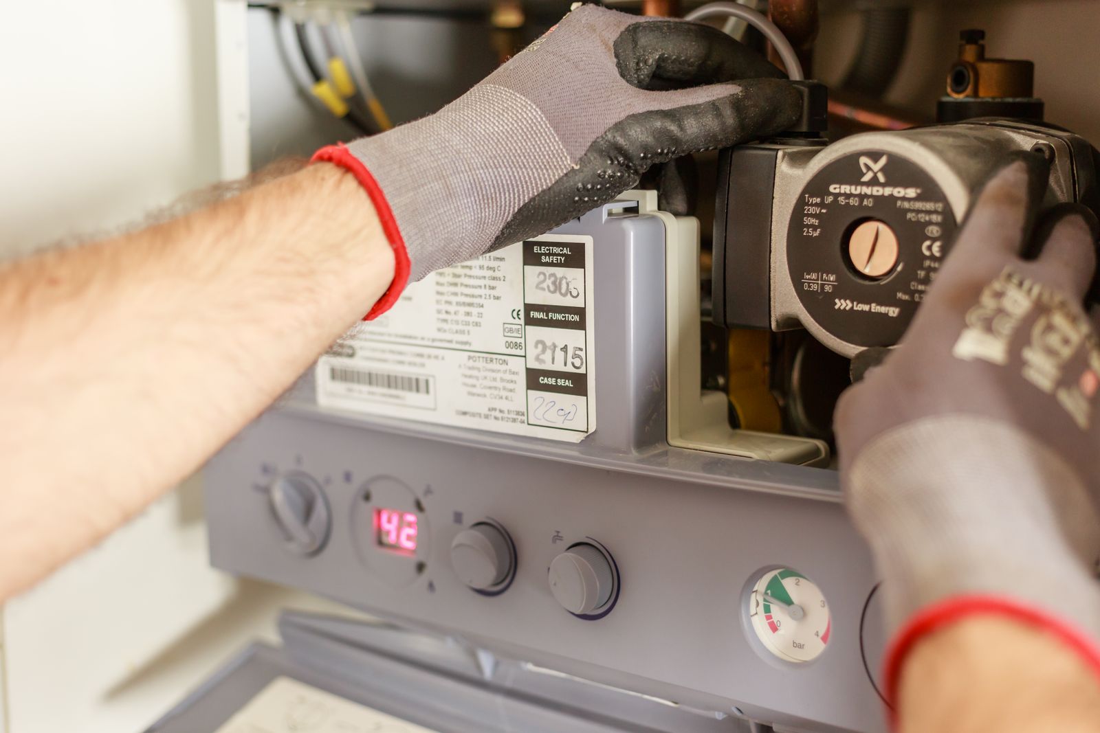 Technician's gloved hands adjusting the controls on a home heating system